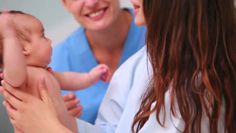 Woman-holding-a-baby-next-to-a-nurse