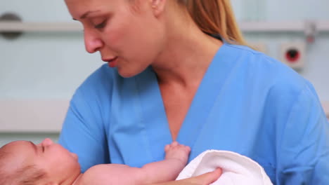 Lächelnde-Krankenschwester-Hält-Ein-Neugeborenes-Baby