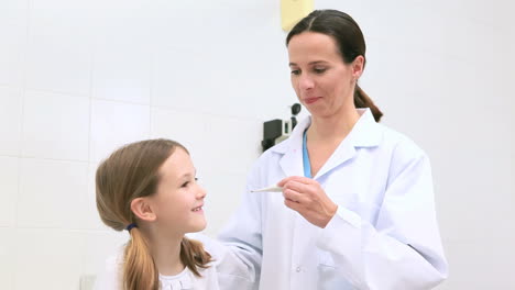 Doctor-checking-fever-of-a-girl-with-a-thermometer-in-her-mouth