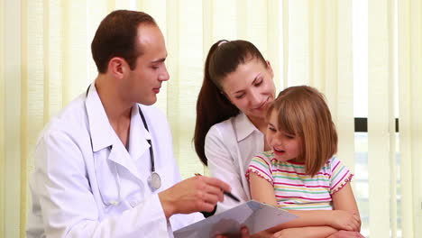 Doctor-talking-to-a-girl-while-she-sits-on-the-knees-of-her-mother