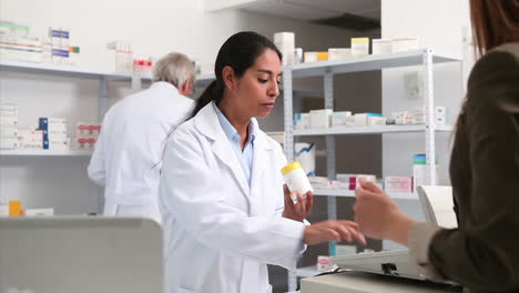 Smiling-female-pharmacist-handing-drugs-to-a-customer