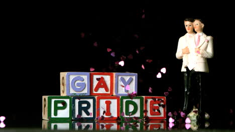 Confetti-falling-on-blocks-spelling-gay-pride-with-gay-cake-topper