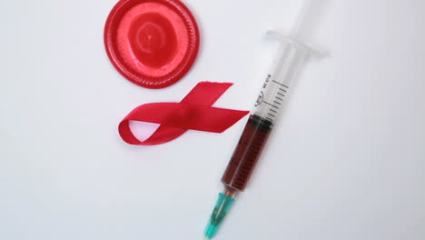 Red-ribbon-condom-and-syringe-with-blood-sample