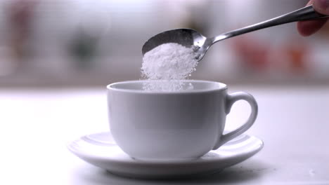 Verter-Azúcar-En-Polvo-De-Una-Cucharadita-En-Una-Taza-Blanca