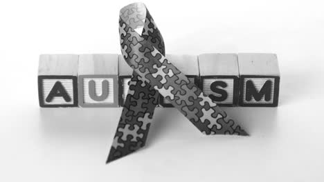 Awareness-ribbon-falling-in-front-of-autism-letter-blocks-in-black-and-white