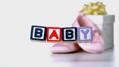 Baby-blocks-falling-beside-booties-and-gift-box