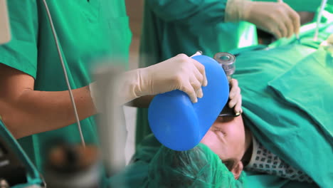 Surgeon-working-on-a-patient-with-a-resuscitation-bag-while-looking-at-a-monitor