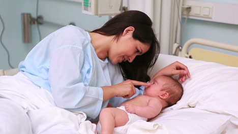 Madre-Sonriente-Con-Su-Bebé-En-Una-Cama