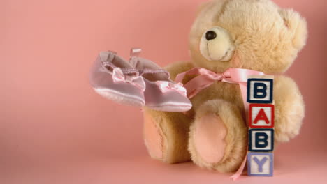 Baby-shoes-falling-next-to-a-teddy-bear-and-baby-blocks