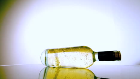 Botella-De-Vino-Blanco-Girando-Sobre-Una-Superficie-Blanca