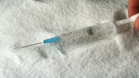 Hand-taking-syringe-out-of-pile-of-sugar