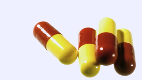 Red-and-yellow-capsule-tablets-dropping-and-bouncing-close-up