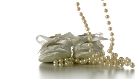 Pearl-necklace-falling-onto-baby-shoes