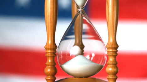 Sand-flowing-through-hourglass-with-american-flag-background