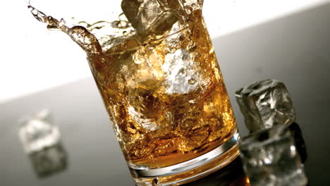 Ice-falling-into-tumbler-of-whiskey-and-ice-