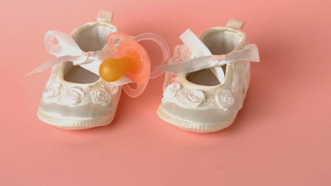 Pink-soother-falling-onto-baby-shoes