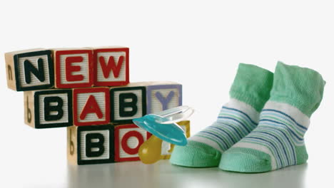 Blue-soother-falling-besides-slippers-and-baby-blocks