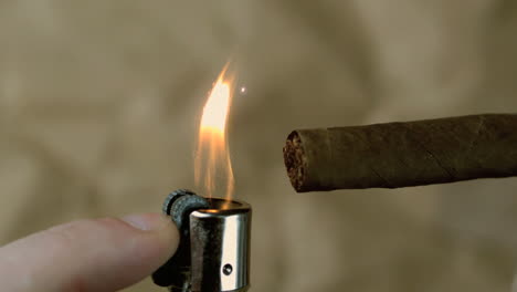 Hand-lighting-a-cigar-on-beige-background