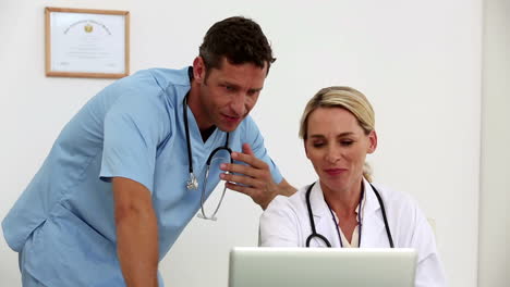 Dos-Médicos-Usando-Una-Computadora-Portátil-Juntos-En-Su-Oficina