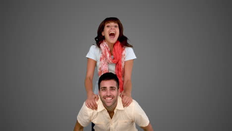 Woman-jumping-on-the-back-of-her-friend-on-grey-background