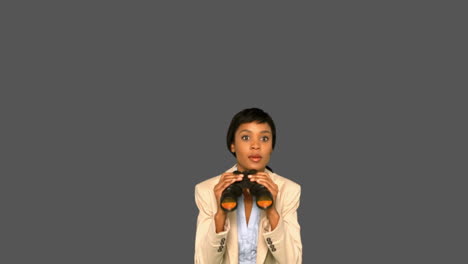 Concentrated-businesswoman-jumping-while-holding-binoculars