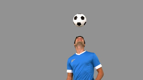 Man-juggling-a-football-with-his-head-on-grey-screen