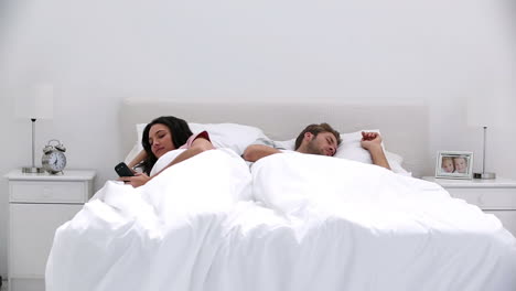 Woman-texting-while-her-partner-is-sleeping