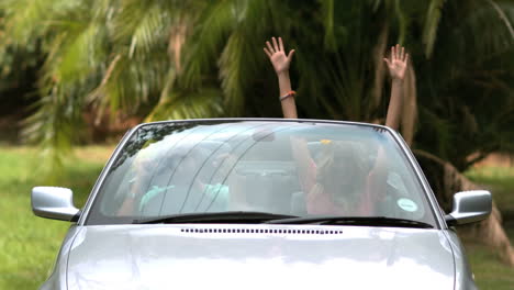 Friends-dancing-and-raising-up-their-hands-in-the-car