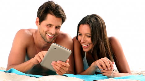 Couple-relaxing-on-the-beach-with-a-tablet-