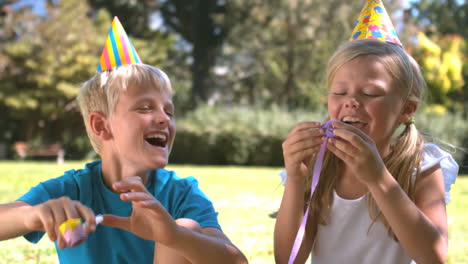 Brother-playing-with-party-horn-next-to-his-sister