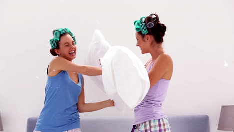 Friends-in-hair-rollers-having-pillow-fight