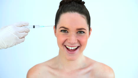 Hand-putting-a-syringe-on-the-forehead-of-a-beautiful-woman