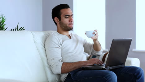 Man-drinking-coffee-while-using-a-laptop