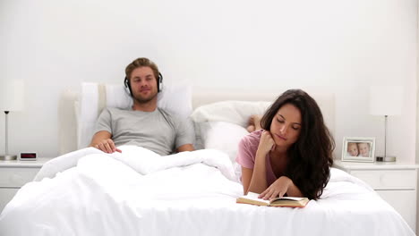 Woman-reading-a-book-while-partner-is-listening-to-music