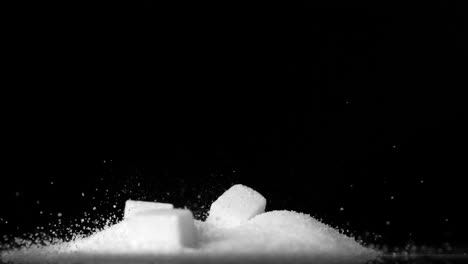 Sugar-cubes-falling-into-pile-of-sugar-on-black-background