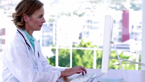 Doctor-typing-at-her-desk-and-smiling
