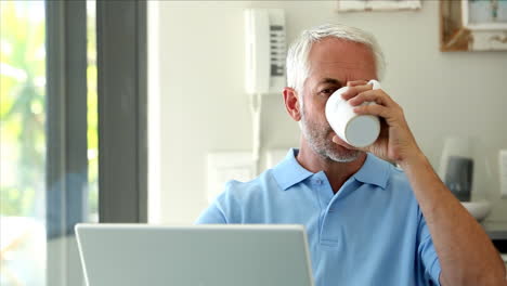 Serious-man-using-his-laptop-while-drinking-a-coffee-