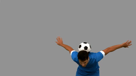 Man-juggling-a-football-with-head-on-grey-screen