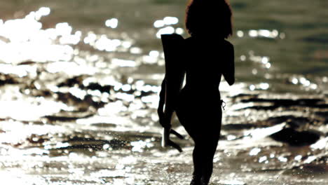 Silhouette-Einer-Frau,-Die-Mit-Ihrem-Surfbrett-Aus-Dem-Meer-Rennt