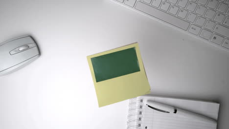 Yellow-post-it-with-green-copy-space-falling-on-office-desk