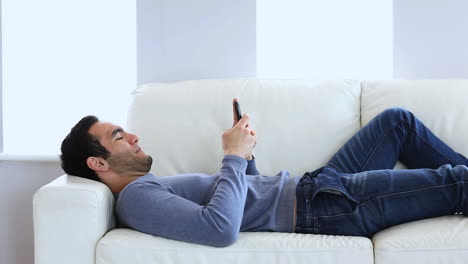 Man-text-messaging-laid-on-the-couch
