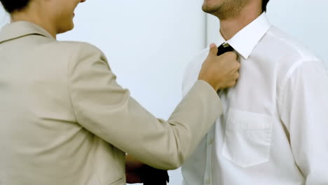 Businesswoman-helping-a-man-tying-his-tie