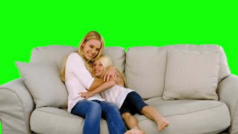 Daughter-jumping-in-the-arms-of-her-mother-in-the-sofa-on-green-screen