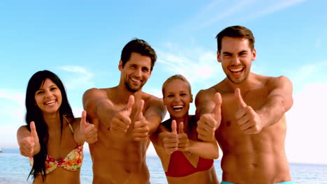 Friends-giving-thumbs-up-to-the-camera-at-the-beach