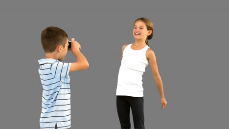 Brother-taking-pictures-of-his-sister-jumping-on-grey-screen