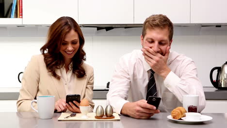 Couple-showing-each-other-their-phones-at-breakfast