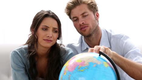 Couple-looking-at-globe-and-picking-travel-destination