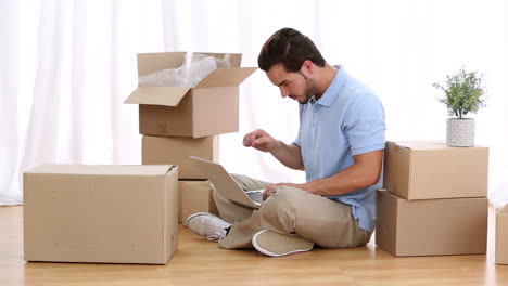 Man-typing-on-his-computer-between-moving-boxes