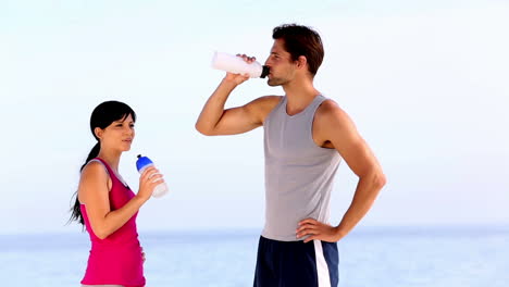 Hombre-Y-Mujer-Bebiendo-Agua-En-La-Playa