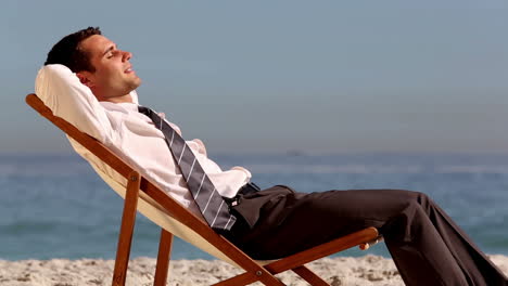 Smiling-businessman-relaxing-on-the-beach